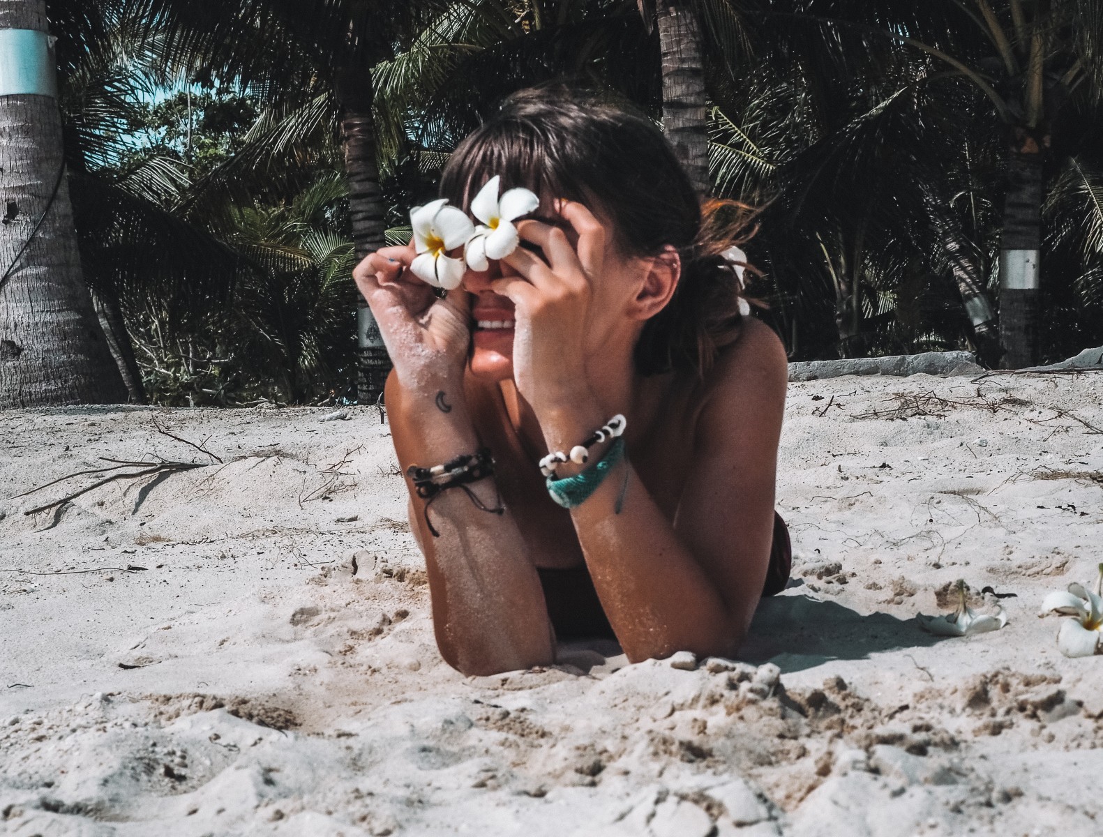 girl holding prangipani flowers on the beach