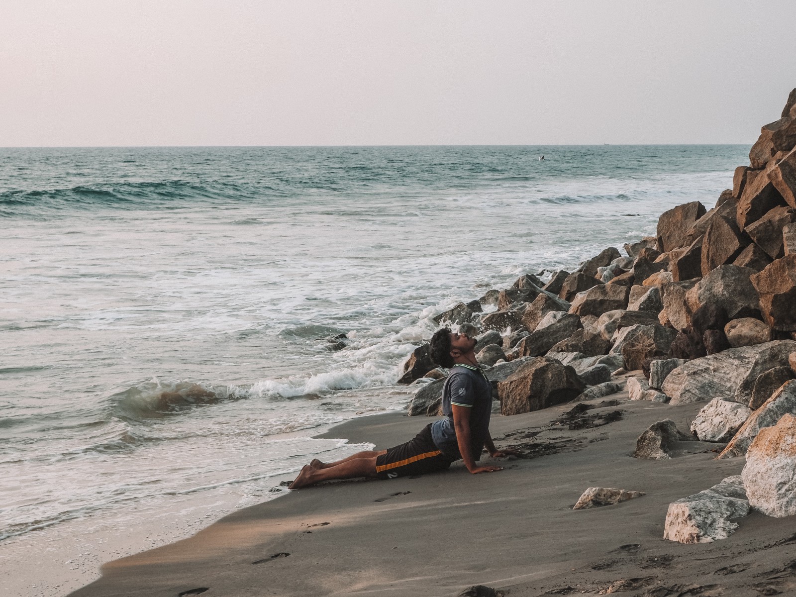 A man practicing yoga on the black beach in Varkala