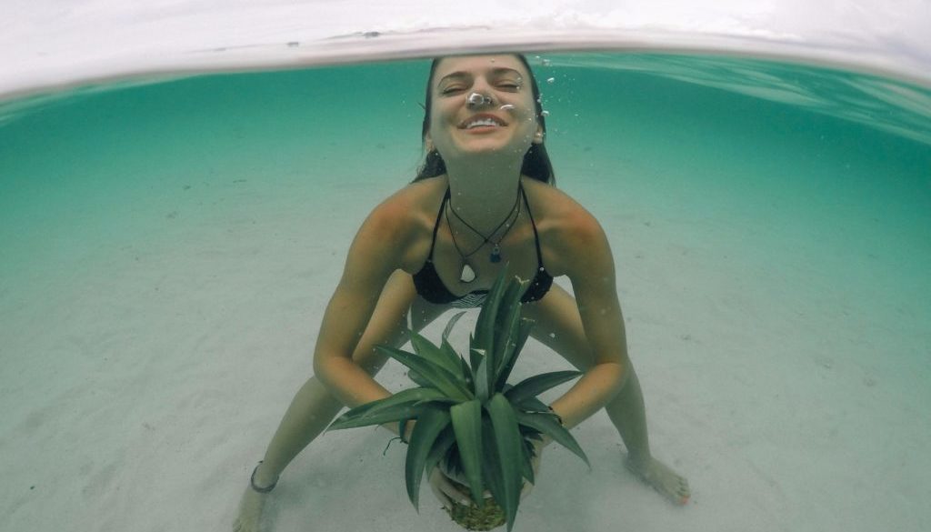 A girl under the water with a pineapple