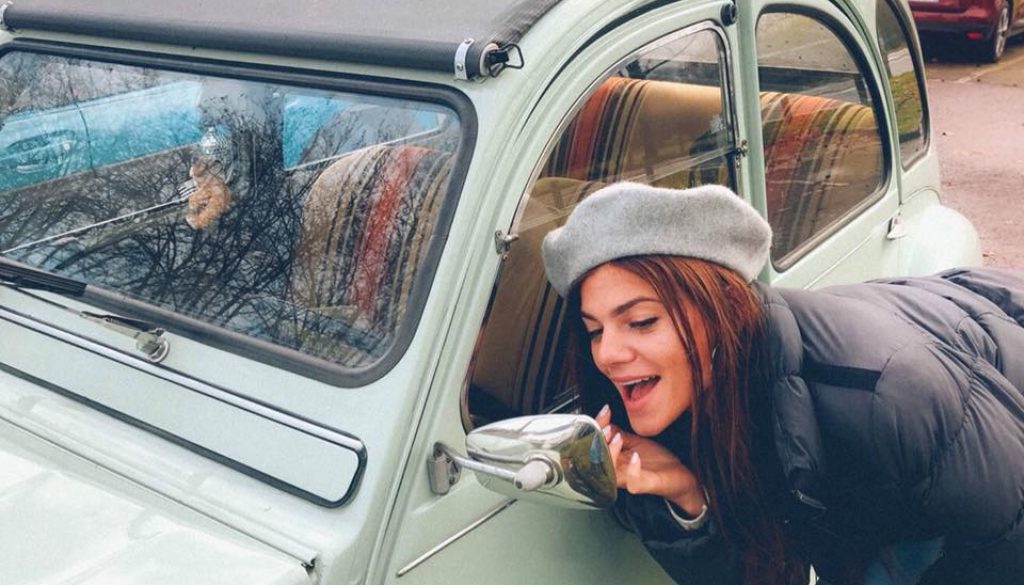 A girl looking at herself in the car wing mirror