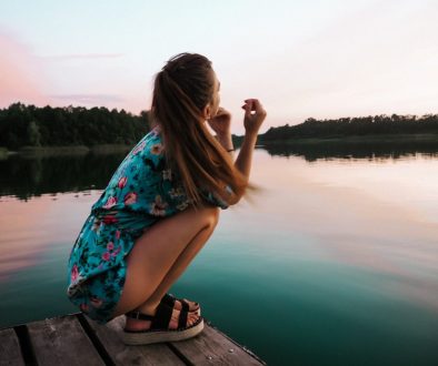 girl crouching by a lake